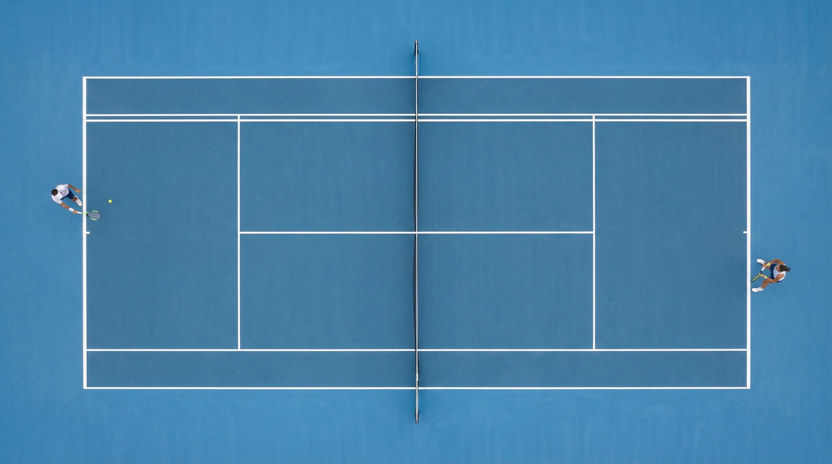 Tennisplatz aus der Vogelperspektive mit zwei Spielern an der Grundlinie