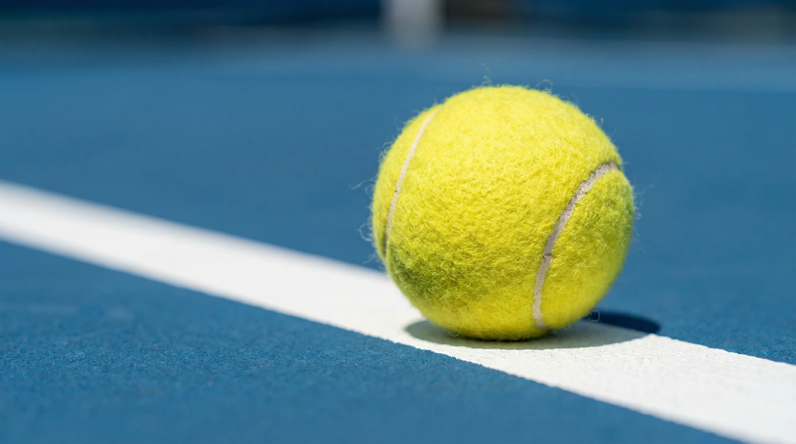 Nahaufnahme eines Tennisballs auf einer weißen Linie auf blauem Hartplatz