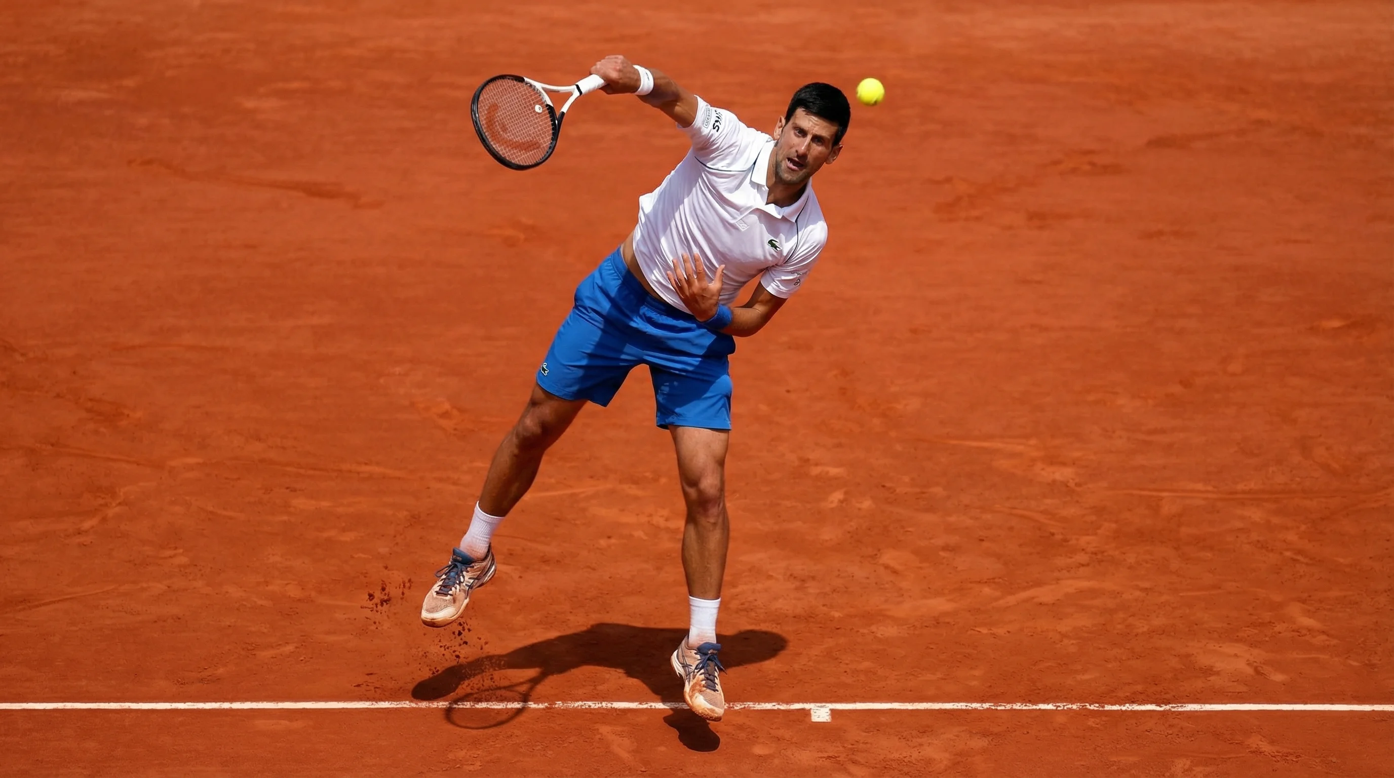 Tennisspieler beim Aufschlag auf einem Sandplatz mit sichtbaren Linienmarkierungen